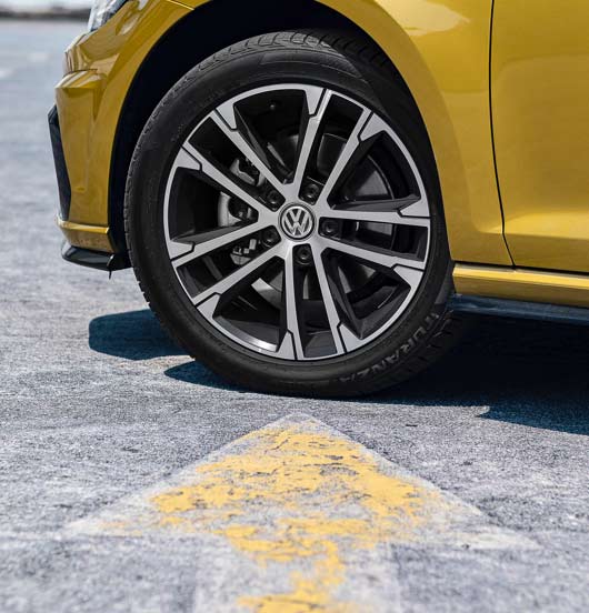 Collage of a woman driving a car with a tire on a gold car